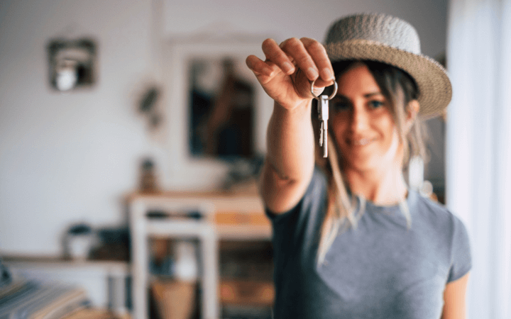 A young woman holds up house keys after being approved for NDIS SDA housing IMG